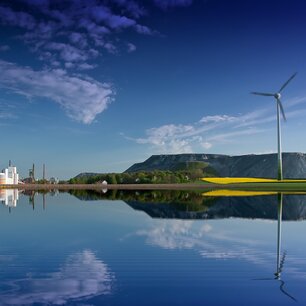 Industrial plant and wind turbine reflected in still water