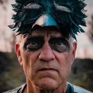 Close-up portrait of a person in a dark feathered mask