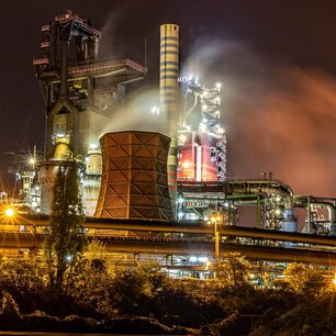 Steel plant lit up at night with rising steam