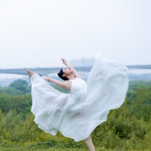 Dancer leaping in a flowing white dress outdoors