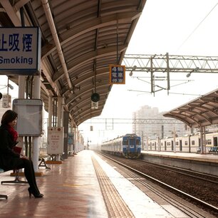 Woman waiting on a bench at a train platform