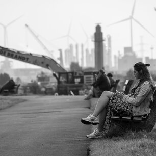 Woman sitting on a bench in an industrial harbor