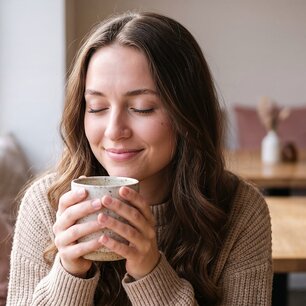 Woman savoring a warm drink at a café table