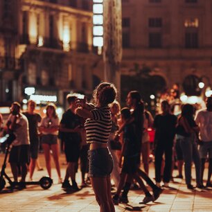 Young woman standing in a busy night-lit plaza