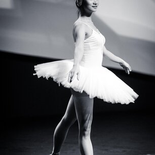 Ballet dancer mid-pose in a tutu on stage