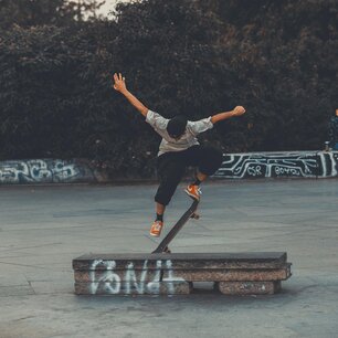 Skateboarder mid-trick over a concrete ledge