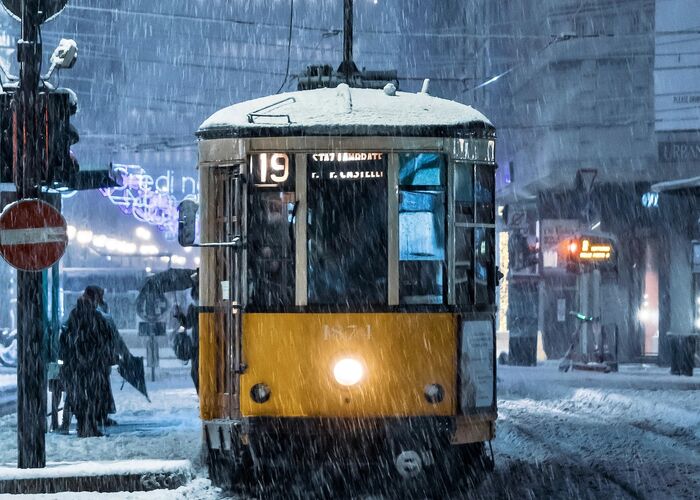 Vintage yellow tram running through a snowy night street