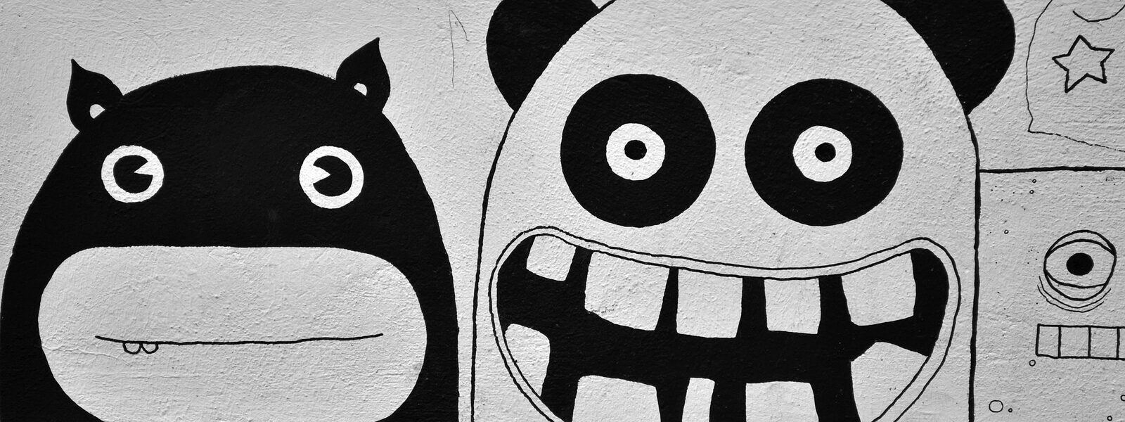 Black-and-white mural of two grinning cartoon monster faces