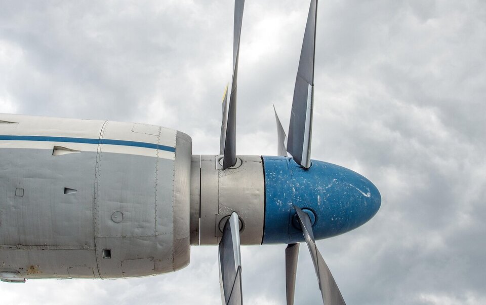 Aircraft propeller and nose against a cloudy sky